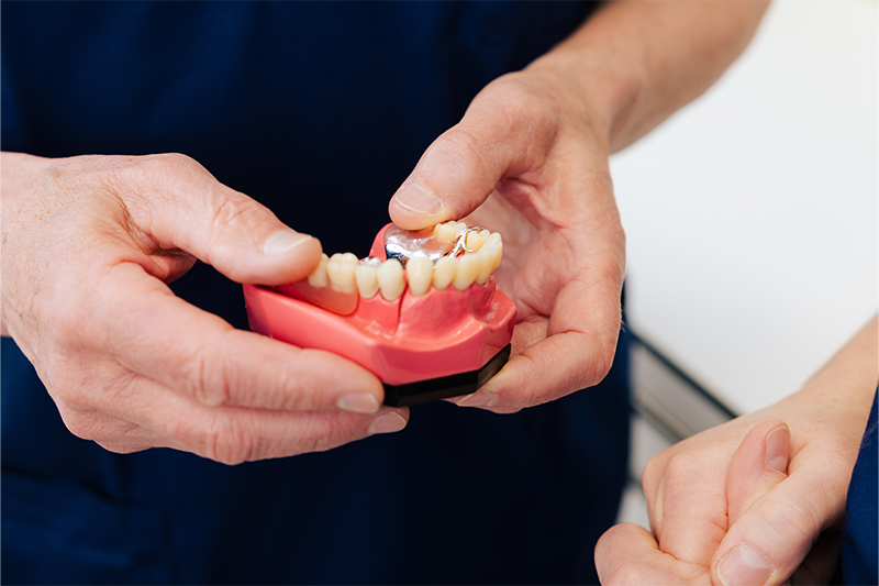 Herr Rosenberger zeigt einer Patientin den gefertigten Zahnersatz.