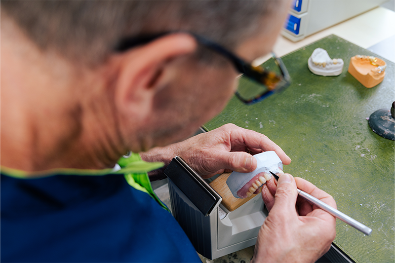 Herr Rosenberger bearbeitet den Zahnersatz eines Patienten.