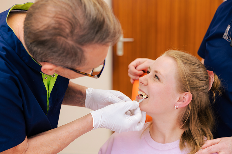 Eine junge Frau bekommt eine Farbanpassung für Ihre Zahnfüllung.