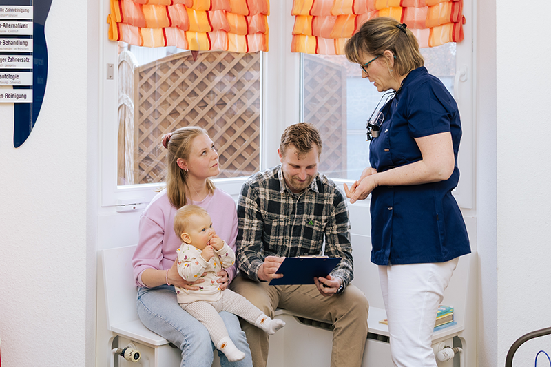 Dr. Weilandt berät ein Elternpaar zur Behandlung von Kinderzähnen.