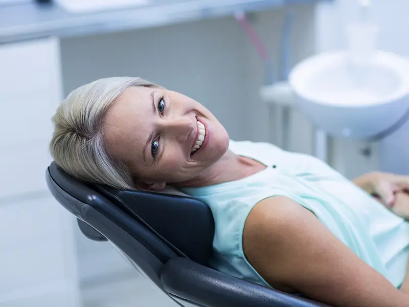 Eine Patientin lächelt nach der Behandlung glücklich in die Kamera. Als Angstpatient wirkt sie sehr erleichtert nach der Behandlung.