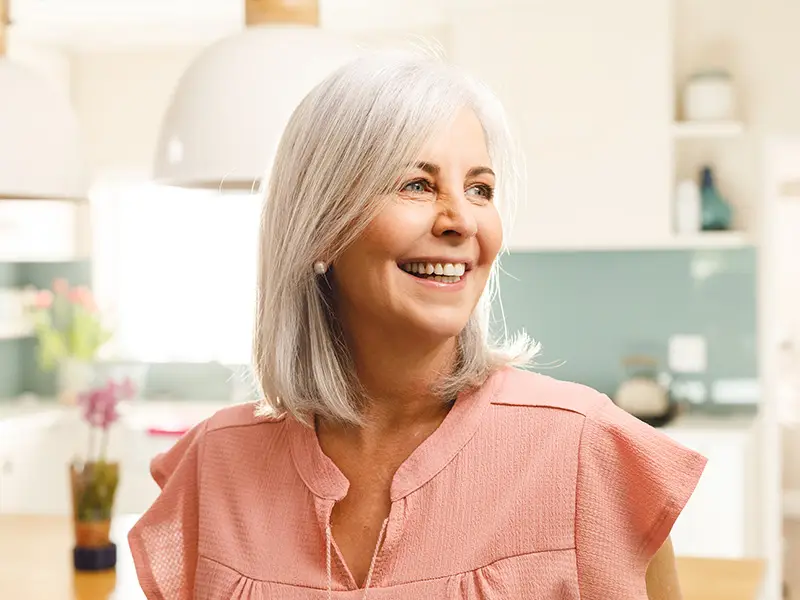 Eine ältere Dame hat gerade ihren Zahnersatz bekommen und ist glücklich.