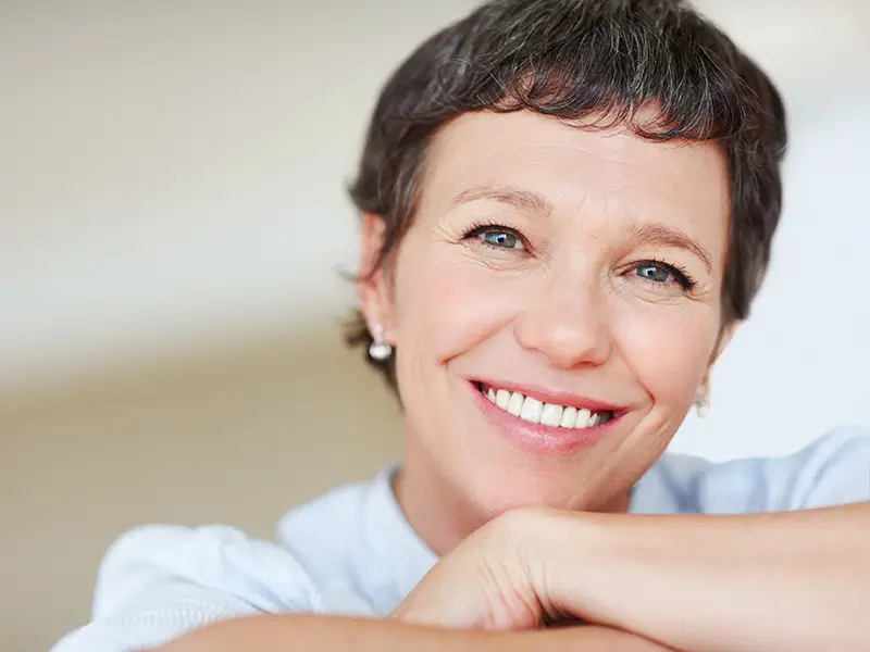 Eine junge Frau lächelt nach ihrer Prophylaxe Behandlung in die Kamera.